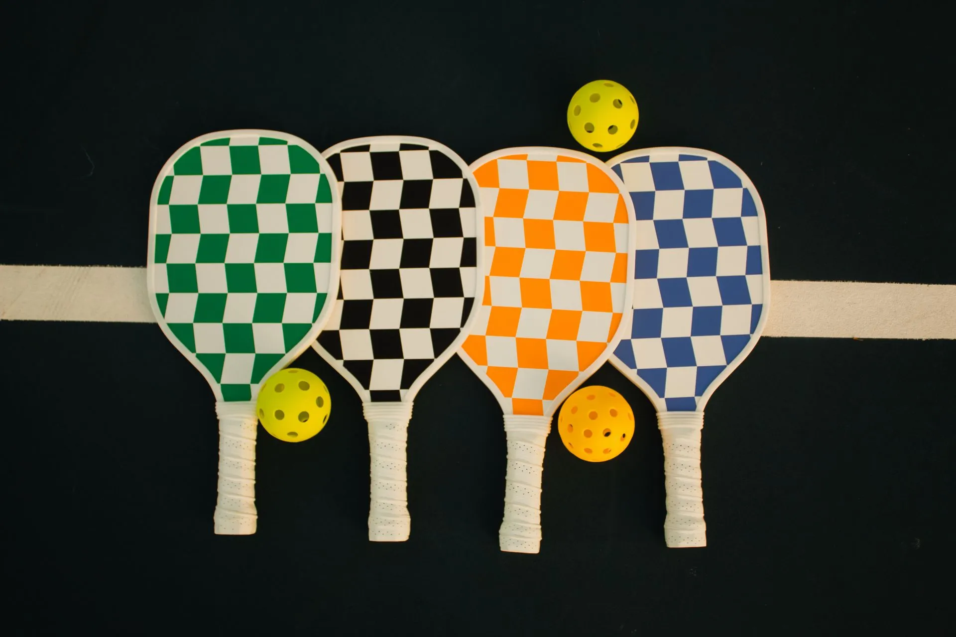 Four checkered paddles lined up with balls