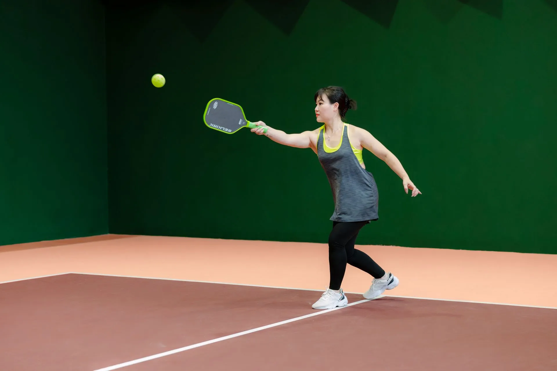 Player reaching for a ball on an indoor court